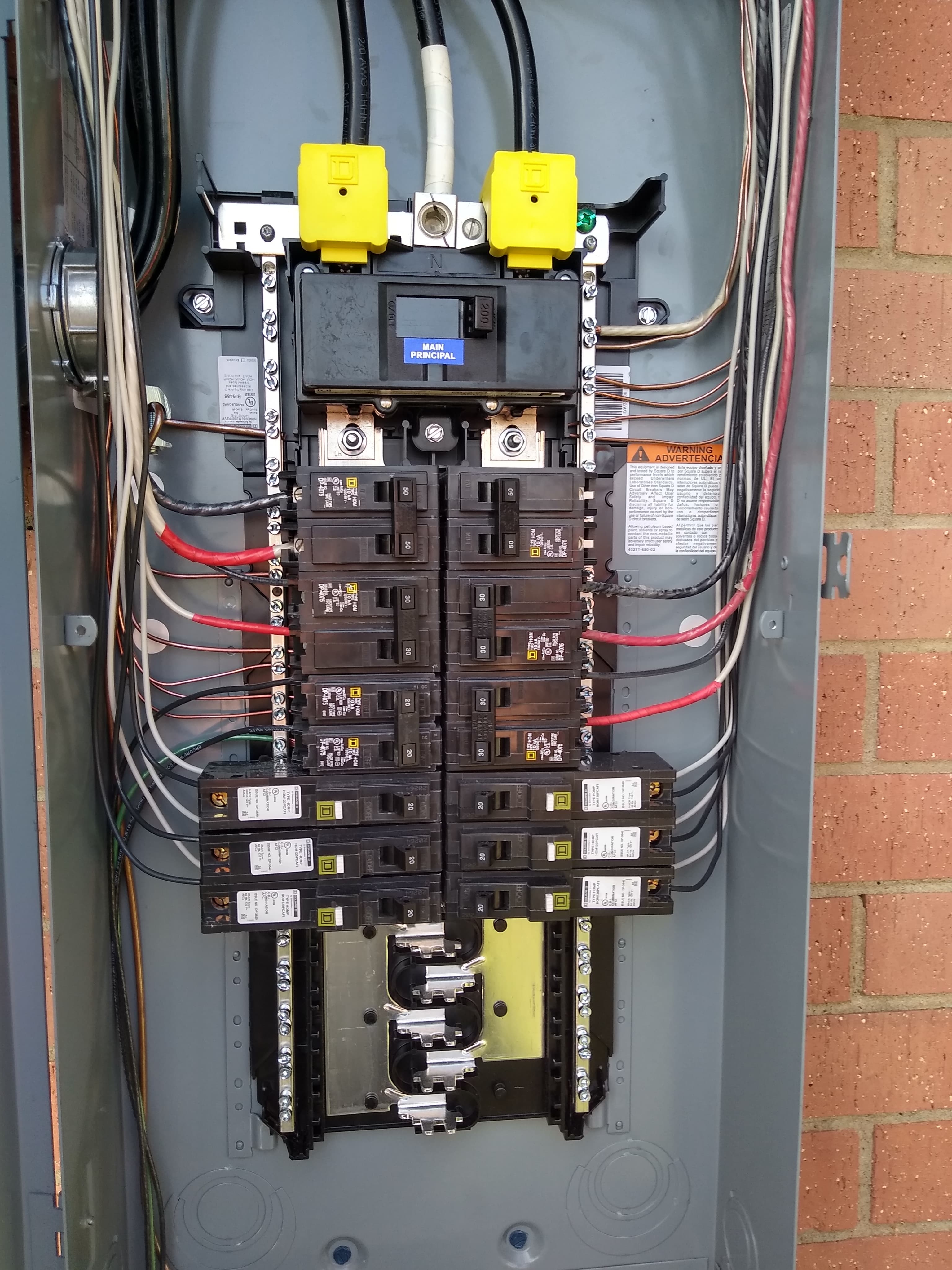 Open electrical panel with main breaker, multiple circuit breakers, and organized colored wiring.